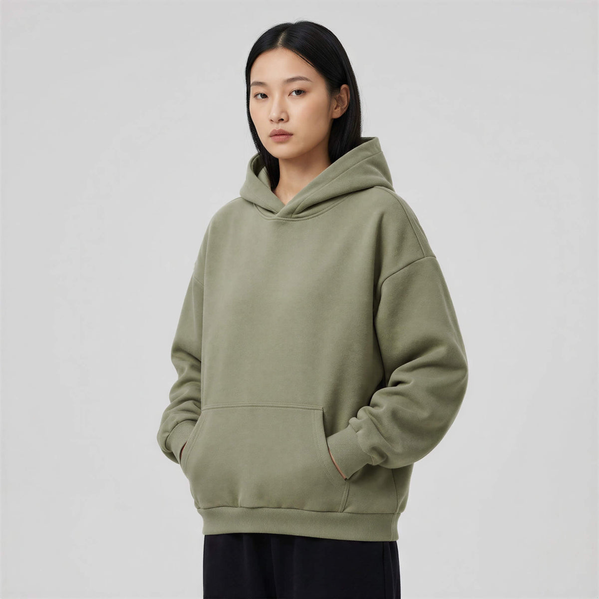 Blank heavyweight oversized hoodie in olive green, featuring a front pocket and a relaxed fit worn by a model.